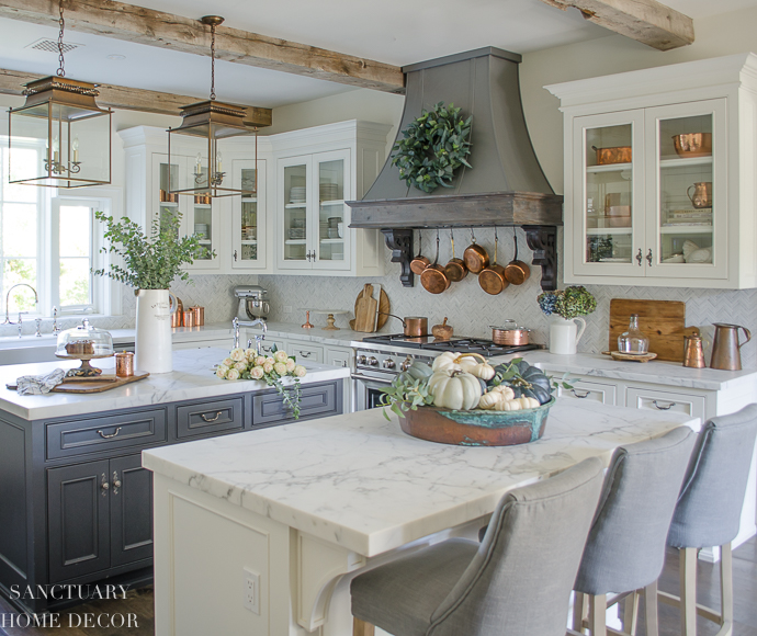 Farmhouse kitchen with fall decorating. Glass front cabinets with copper accents. Range hood with wreath. Copper pots