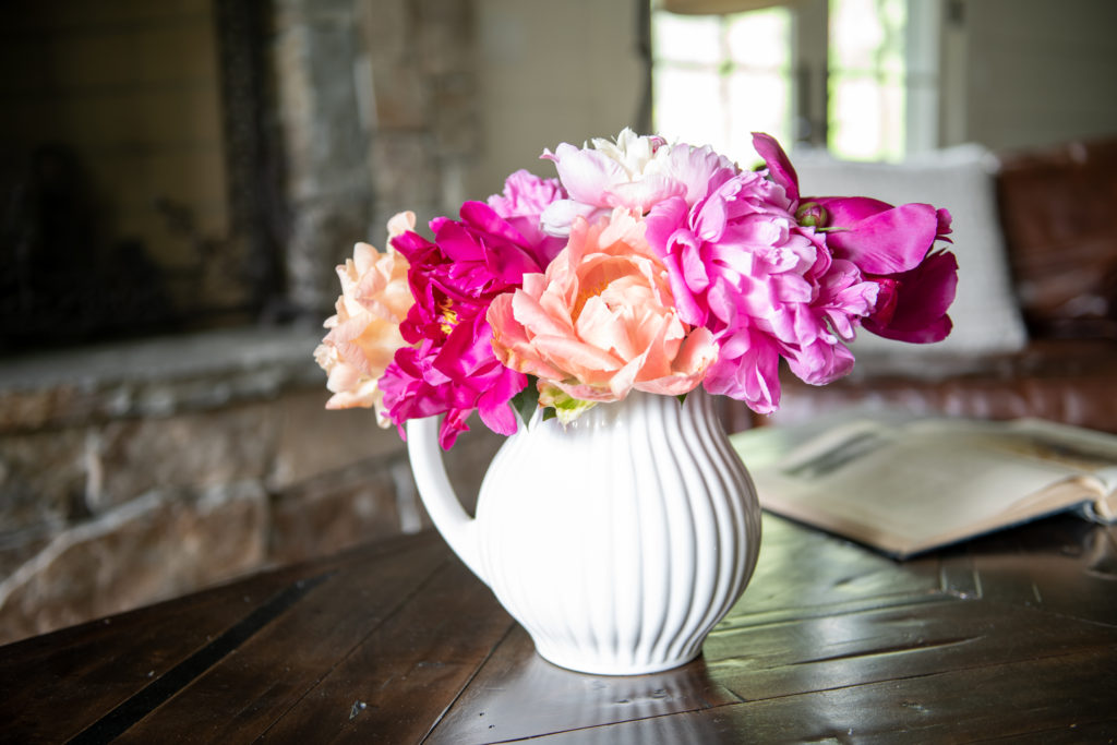 rustic cabin in the woods with peonies in white pitcher
