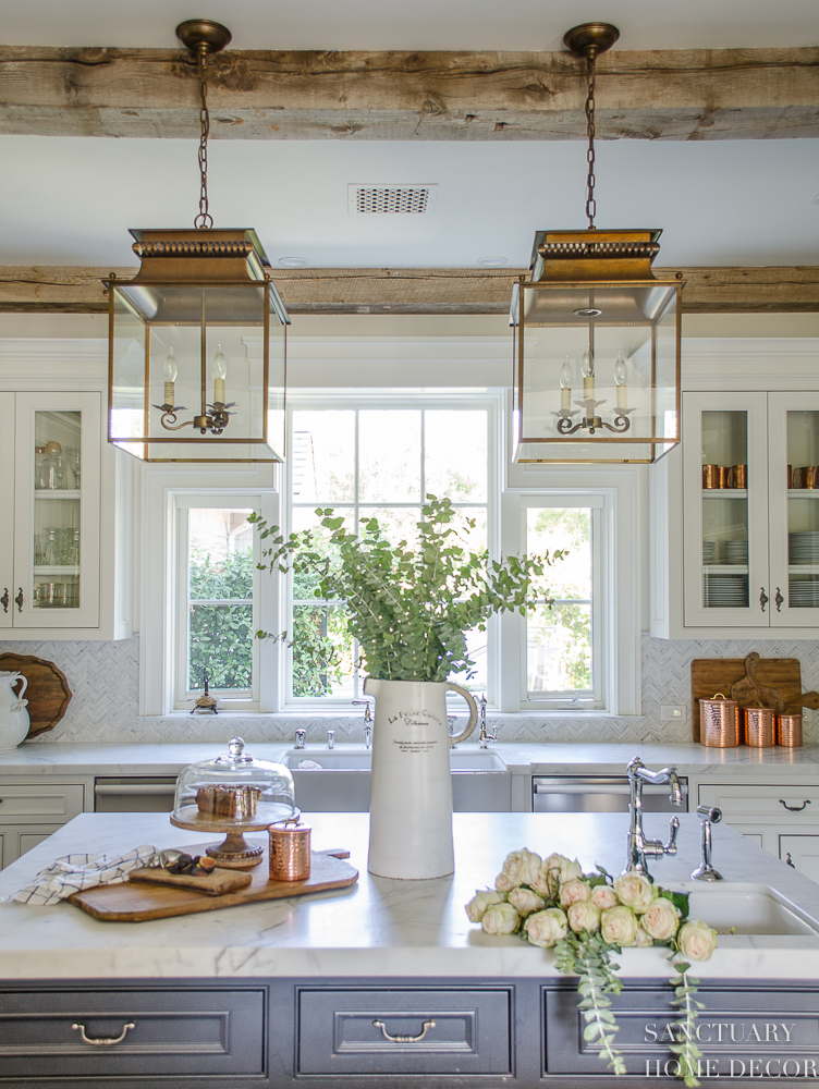 5 Minute Fall Decorating Tips-White country kitchen with pendant lights and glass front cabinets. White marble countertops.