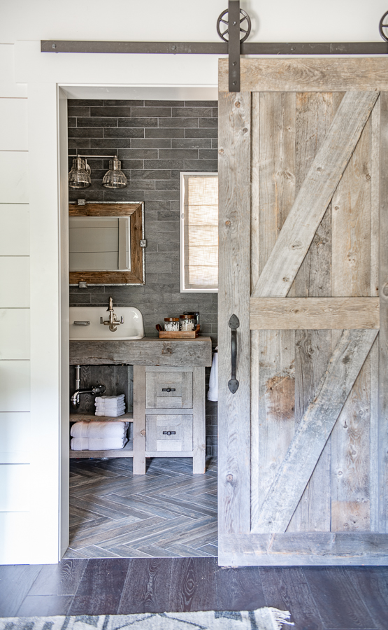 Rustic Barn door, Bath with barn wood vanity, herringbone floors and Smith and Noble Roman Shades