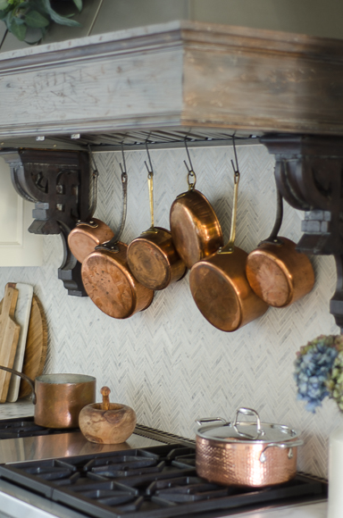 Hanging copper pots behind range.