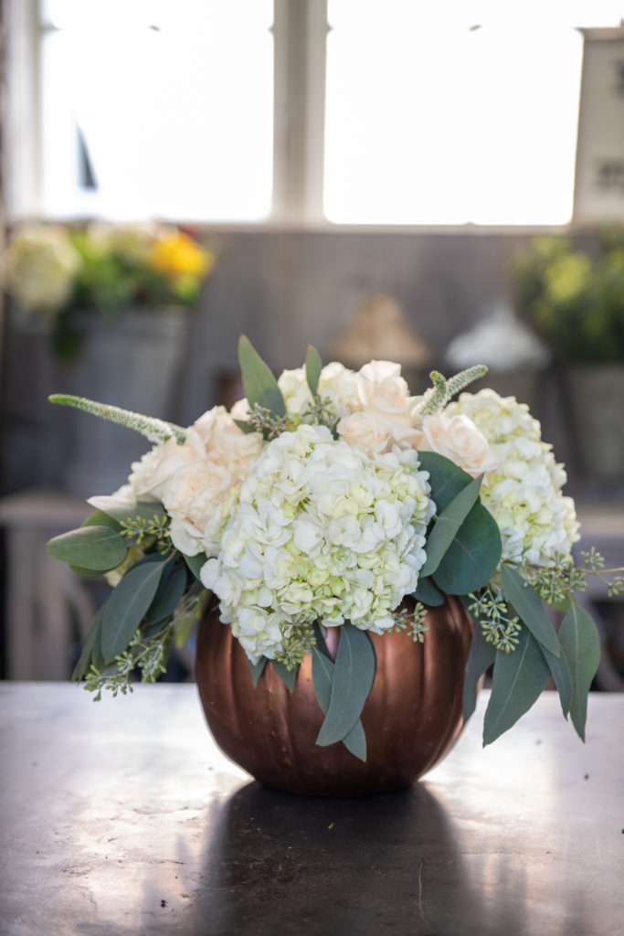 hydrangea and rose centerpiece in a copper pumpkin